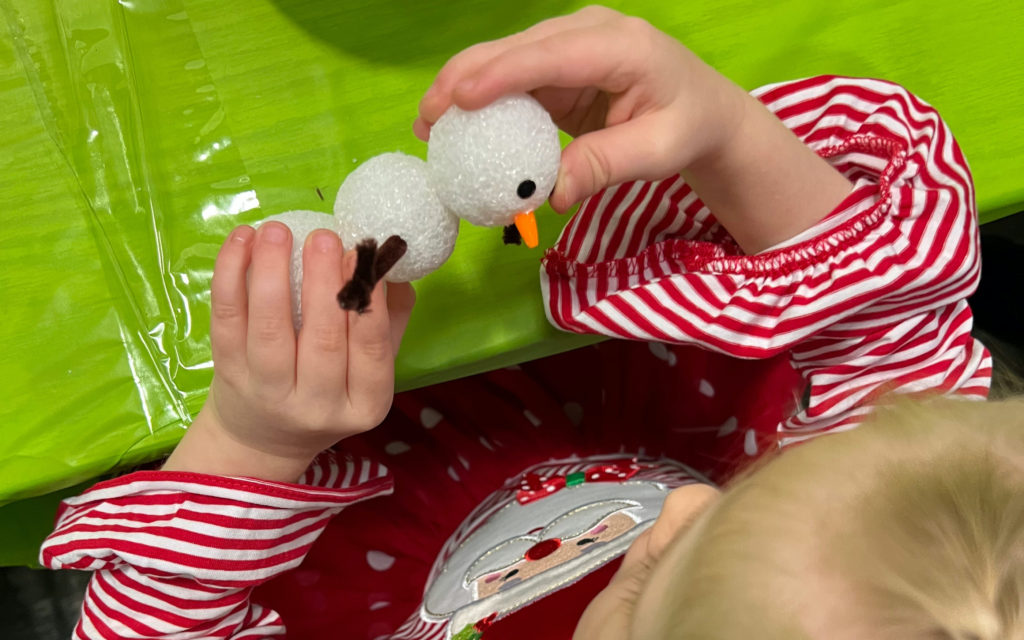 Young girl builds FloraCraft foam snowman at Christmas party.