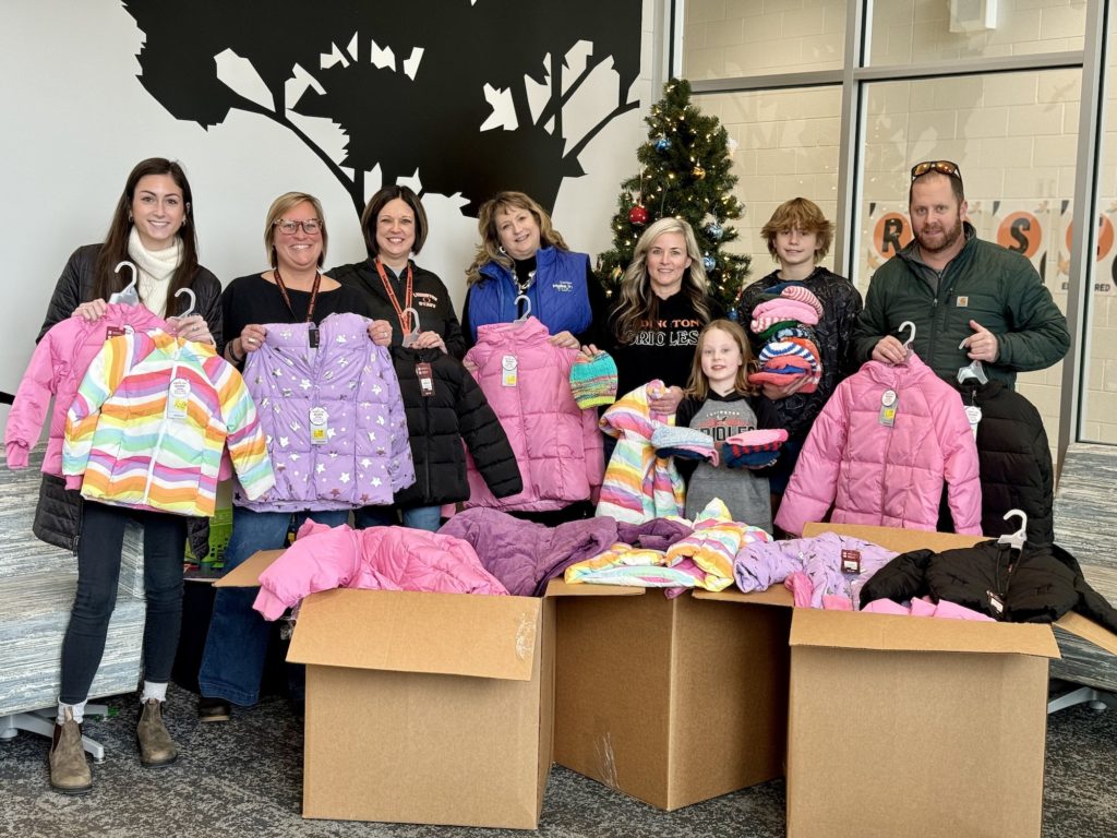 FloraCraft team members stand around boxes of donated coats and winter items.