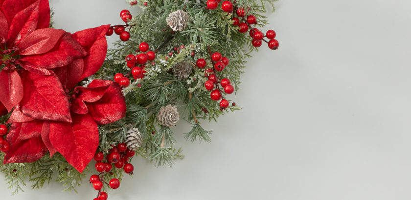 A snapshot of a Christmas wreath with red poinsettias and berries.